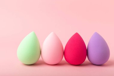 Güzellik karışımı. Pembe arka planda renkli güzellik süngerleri. Vakıf ve kapatıcı gibi ürünleri uygulamak ve harmanlamak için kozmetik araç. Uzayı kopyala metin için yer.