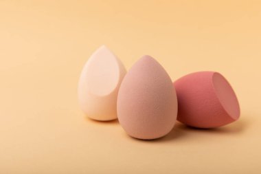 Güzellik karışımı. Bej arka planda renkli güzellik süngerleri. Vakıf ve kapatıcı gibi ürünleri uygulamak ve harmanlamak için kozmetik araç. Uzayı kopyala metin için yer.