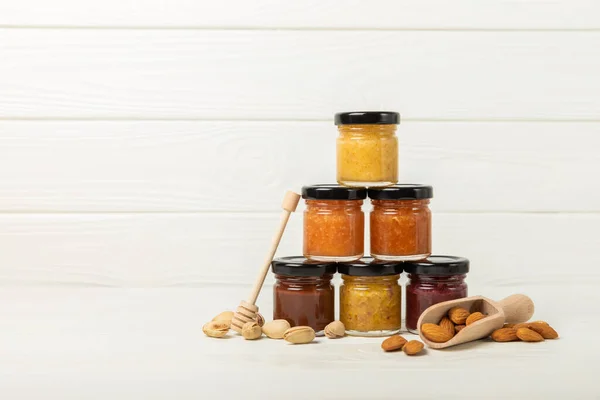Honey jam with nuts on white texture wood. Assorted honey. Honey in pistachios and almonds. Environmentally friendly product. Vitaminized jam. Cold remedy.Copy space