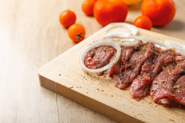 Soğan ve biberli taze çiğ biftek. Arka planda taze sebzeler. Et salamurası. Biftek..