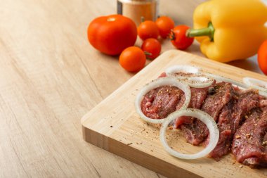 Soğan ve biberli taze çiğ biftek. Arka planda taze sebzeler. Et salamurası. Biftek..