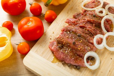 Soğan ve biberli taze çiğ biftek. Arka planda taze sebzeler. Et salamurası. Biftek..