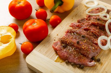 Soğan ve biberli taze çiğ biftek. Arka planda taze sebzeler. Et salamurası. Biftek..