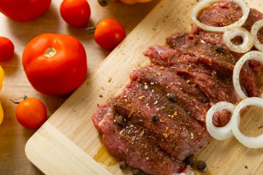 Soğan ve biberli taze çiğ biftek. Arka planda taze sebzeler. Et salamurası. Biftek..