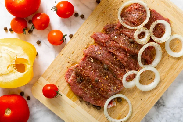 Soğan ve biberli taze çiğ biftek. Arka planda taze sebzeler. Et salamurası. Biftek..