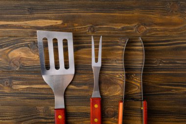 Kahverengi desenli arka planda kullanılmış barbekü araçları.