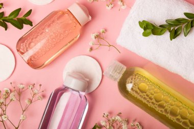 Micellar temizleyici su, çiçekler ve pamuklu pedlerle pembe arka plan, üst manzara. Mesaj için yer. Düz taban. MOCAP