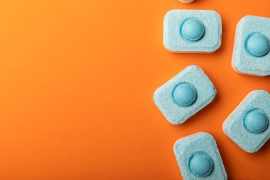 Turuncu arka planda su yumuşatıcı tabletleri. Metin için yer. Kopya için yer. Üst görünüm. Yakın plan.