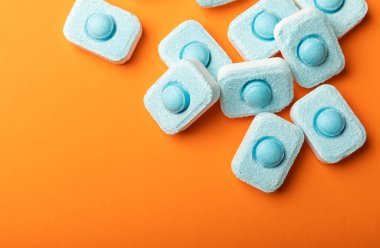 Turuncu arka planda su yumuşatıcı tabletleri. Metin için yer. Kopya için yer. Üst görünüm. Yakın plan.