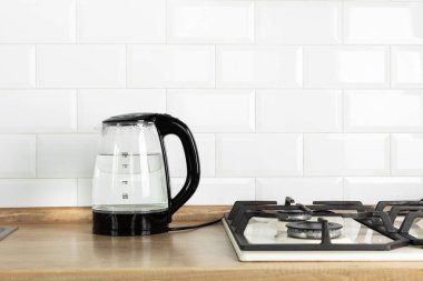 Modern electric transparent kettle on a wooden table in the kitchen.Kettle for boiling water and making tea.Home appliances for making hot drinks.Space for copy.Place for text.