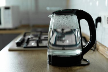 Modern electric transparent kettle on a wooden table in the kitchen.Kettle for boiling water and making tea.Home appliances for making hot drinks.Space for copy.Place for text.