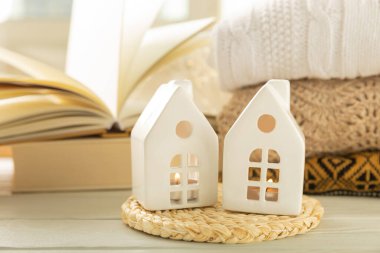 İçinde yanan bir mum olan küçük bir Noel evi şamdanı. Arka planda kitap ve kışlık süveterler. Gayrimenkul kavramı, tatil.