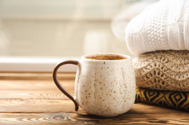 Sonbahar. Sonbahar kompozisyonu, bir fincan sıcak kahve ve ahşap desenli bir masada sıcak bir kazak. Mevsimlik, sabah sıcak kahveleri. Rahatlatıcı ve hayat dolu. İçi rahat.