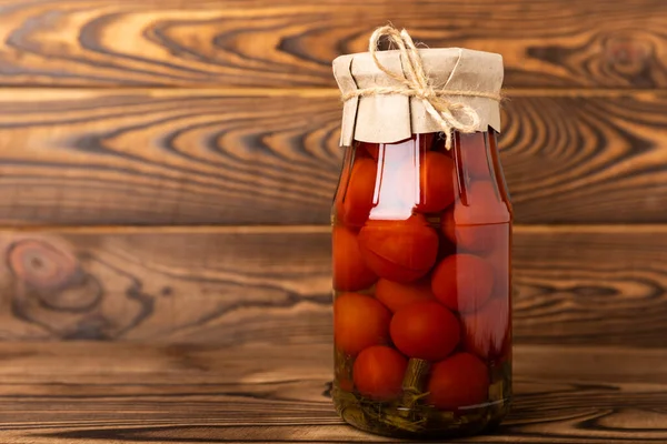 Pickled tomatoes in a jar on a brown wooden background. Food supplies. Healthy food. Harvesting. copy space. Place for text.