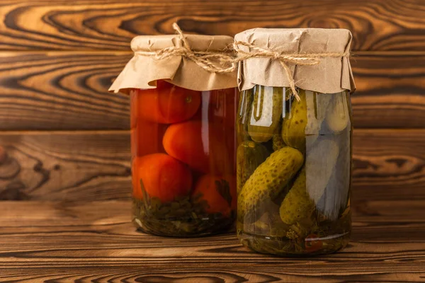 Jars with pickled vegetables. Pickled food.Jars of pickled vegetables: cucumbers and tomatoes on a rustic wooden background. Pickled and canned foods.