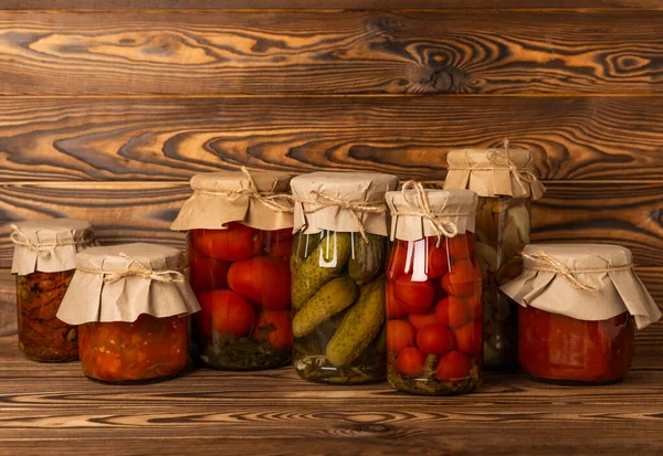 Jars of pickled vegetables. Marinated food.Assortment of homemade jars with a variety of marinated and pickled vegetables on a wooden table. Housekeeping and harvesting.
