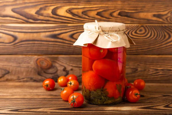 Pickled tomatoes in a jar on a brown wooden background. Food supplies. Healthy food. Harvesting. copy space. Place for text.