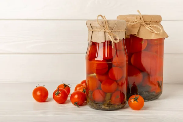 Pickled tomatoes in a jar on a white wooden background. Food supplies. Healthy food. Harvesting. copy space. Place for text.