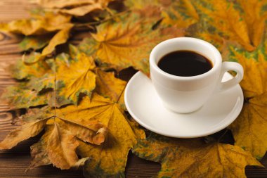 Sonbahar. Ahşap bir masada sonbahar yaprakları ve bir fincan sıcak kahve. Mevsimlik, sabah kahvesi, pazar dinlendirici ve durgun hayat kavramı. Sonbahar kompozisyonu yatıyordu. Haftasonu konsepti..