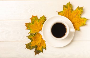 Sonbahar. Ahşap bir masada sonbahar yaprakları ve bir fincan sıcak kahve. Mevsimlik, sabah kahvesi, pazar dinlendirici ve durgun hayat kavramı. Sonbahar kompozisyonu yatıyordu. Haftasonu konsepti..