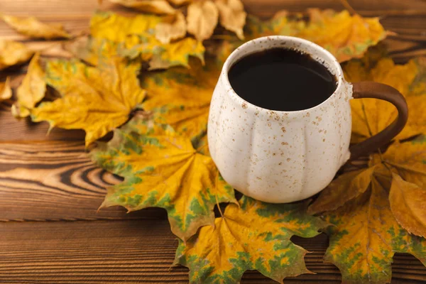 Autumn.Autumn leaves and a hot cup of coffee on a wooden table. Seasonal, morning coffee, Sunday relaxing and still life concept.Flat lay autumn composition.Autumn weekend mood concept.