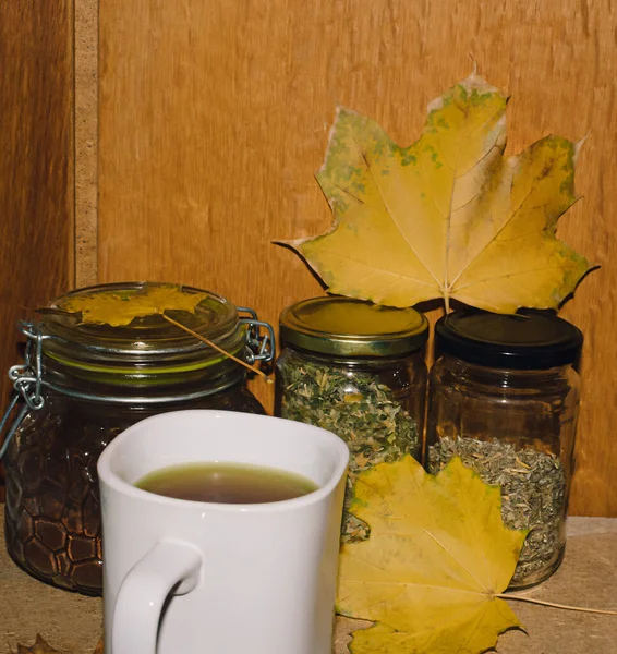 Szklane Butelki Mieloną Kawą Herbaty Żółtymi Liśćmi Stole Białą Filiżanką — Zdjęcie stockowe