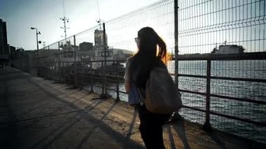 Genç esmer, liman şehrinin rıhtımında uzun bir sörf tahtasına biniyor.