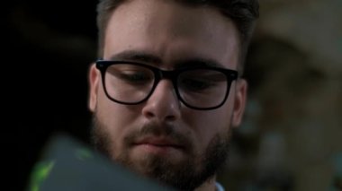 Gözlüklü adam, yakın plan belgeleri inceliyor.