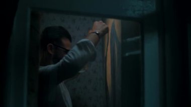 Beyaz gömlekli genç adam sinirlendi ve duvara yumruk attı.