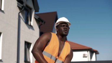 Üniformalı kaslı Afrikalı Amerikalı inşaat alanında balyoz sallıyor..