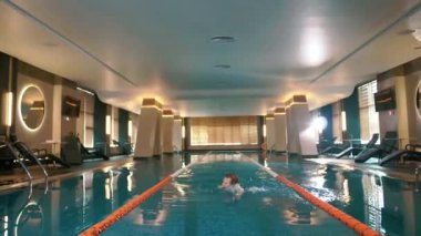 Spor yüzücüsü çatıdaki kapalı havuzda hızla yüzer.