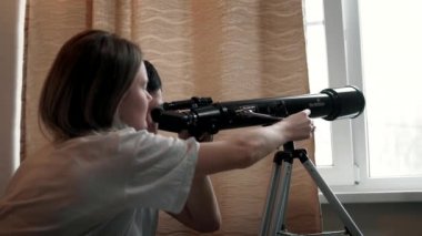 Mutlu çift, pencerenin kenarındaki teleskopla yıldızları inceliyor ya da uzaktan komşularını izliyorlar.