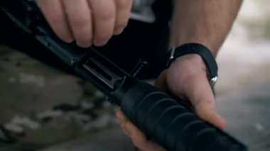 Pompalı tüfeği pompalı tüfekle şarj ediyorum. Pompalı mermileri doldur. Dövmeli ve kollu bir adam.