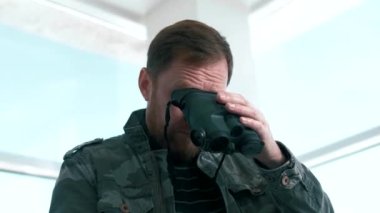 Male secret agent looks through a special thermal imaging binoculars