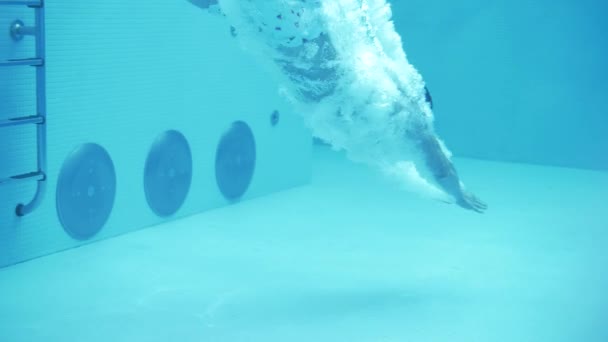 ショートパンツの男は澄んだ水でプールに飛び込む スローモーション — ストック動画