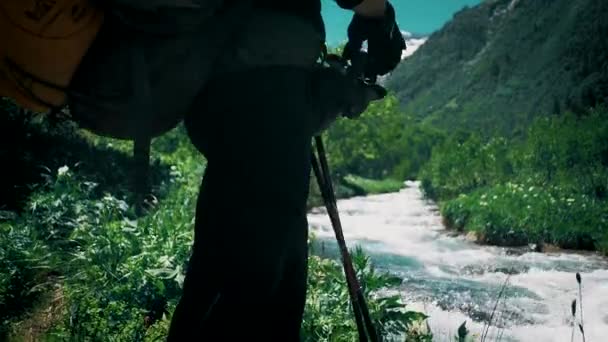 背着大背包的旅行者站在山河边 望着白雪覆盖的山顶 — 图库视频影像