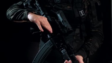 Asker siyah bir arka planda silahına bir civata takar.