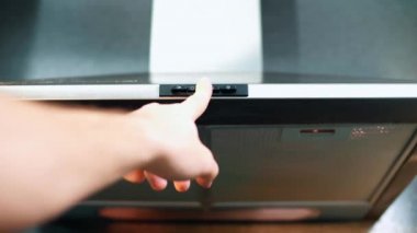 Modern bir mutfağın elektronik kaputunu açan ve kapatan bir kız.