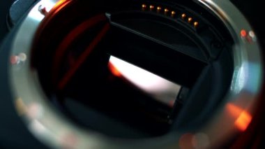 Aynaya yakın çekim ve profesyonel bir kamera matrisi. Kamera lensinin süngüsünün yakın çekim görüntüsü. Fotoğraf makinesinde neon ışığı