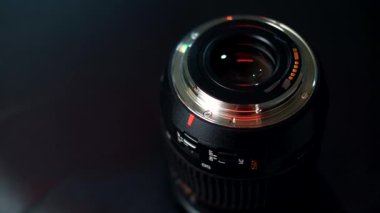 Profesyonel kamera merceği montajı, altın neon ışıklı siyah zemin üzerinde izole edilmiş.