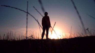 Gün batımında dizlerinin üstüne çöken bir adamın silueti.