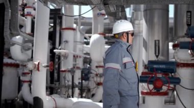 Profesyonel petrol işçisi petrol boru hattının valflerini ve vanalarını kontrol ediyor.