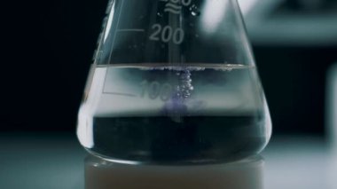 Laboratuvar asistanı test tüpünde analiz için reaksiyonları karıştırıyor. Yavaş çekim