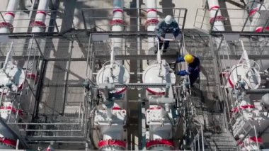 Petrol işçileri petrol boru hattının teknolojik biriminde büyük bir vana çeviriyorlar.