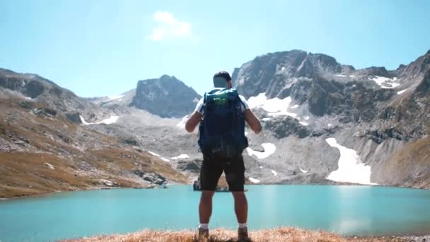 リュックを背負った男が山の湖で休んでいる — ストック動画