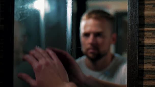 Man Veegt Een Misvormde Spiegel Met Zijn Hand Kijkt Naar — Stockvideo