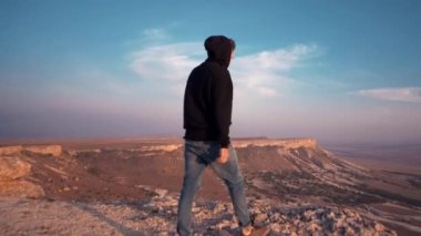 Kapüşonlu genç adam kanyonda seyahat ederken güzel bir manzaraya hayran.