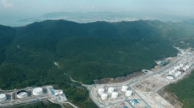Yoğun bitki örtüsüyle çevrili büyük petrol rafinerisi ve depolama tesisi.