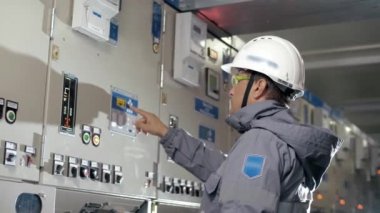 Sert şapkalı elektrik santrali çalışanı yüksek voltaj kalkanındaki düğmelere basıyor