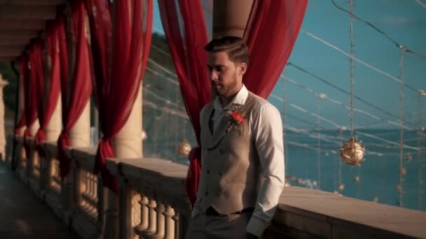 穿着古典服装的年轻英俊男子站在一个古式的美丽的地方 望着大海 — 图库视频影像